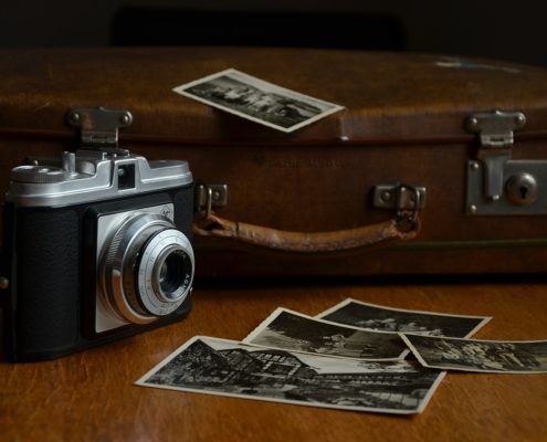 An old camera, a suitcase, and some black and white photos.