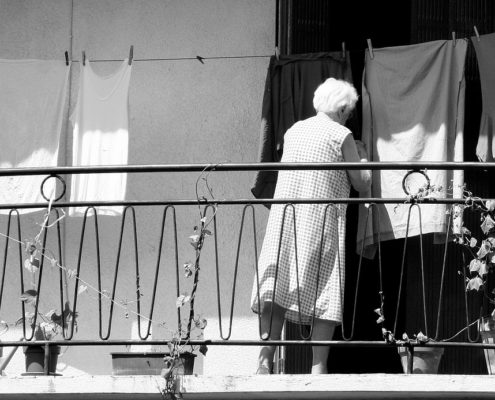 A woman hanging laundry on her porch.