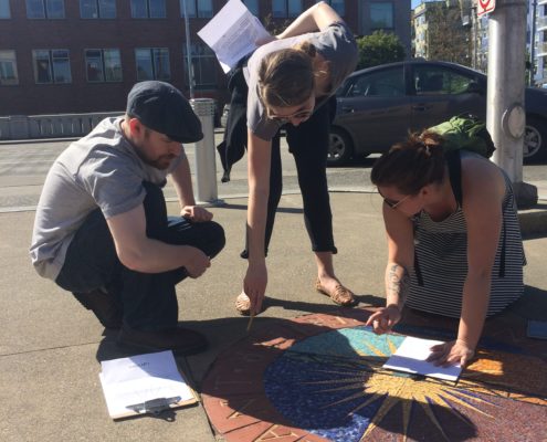 Players inspecting a sidewalk mosaic for clues