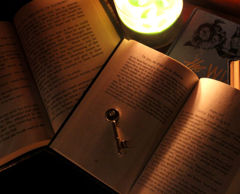 Photo of open books with a key and a candle
